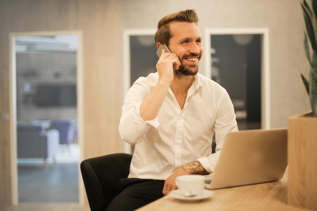 pexels-photo-3760263-3760263 Happy businessman in white shirt on phone call at modern office desk with laptop.